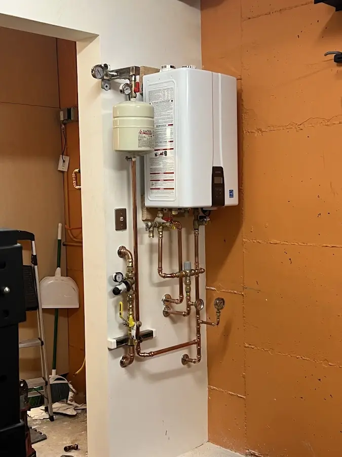 Plumbing technician inspecting water heater connections in Westfield